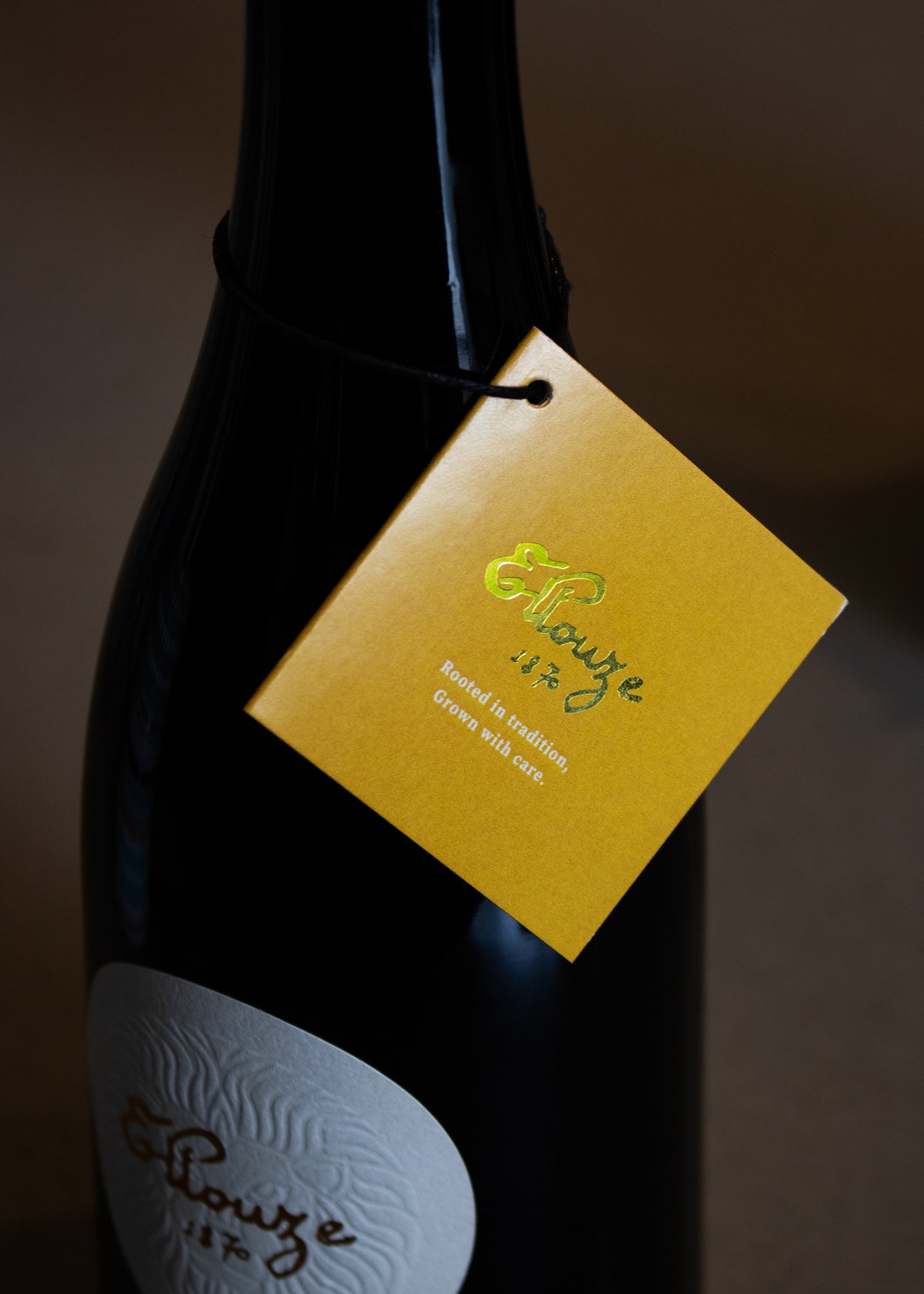 Close-up of Ellouze 1870 Tag and Embossed Logo on Delicate Organic Extra Virgin Olive Oil Bottle